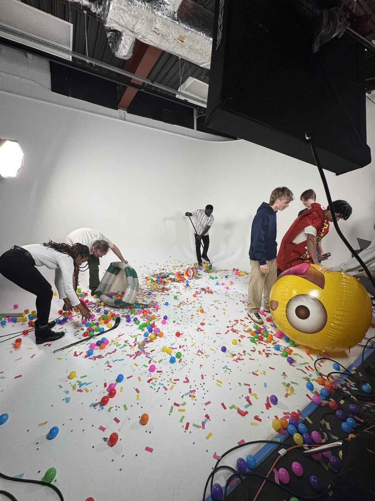 Crew resetting colourful props and confetti under studio lighting