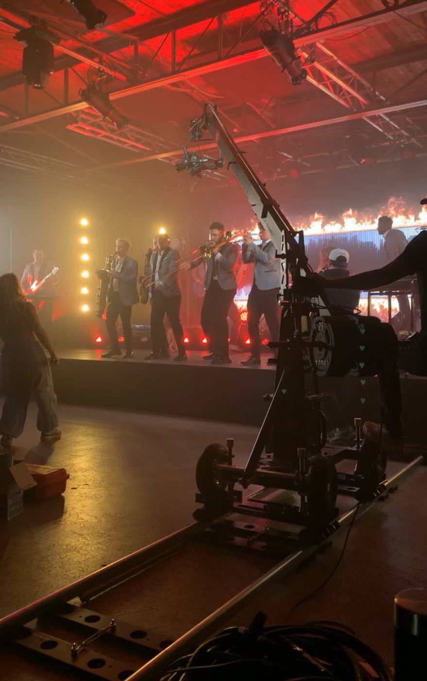 A camera crane reaching over a full live production and a brightly lit stage