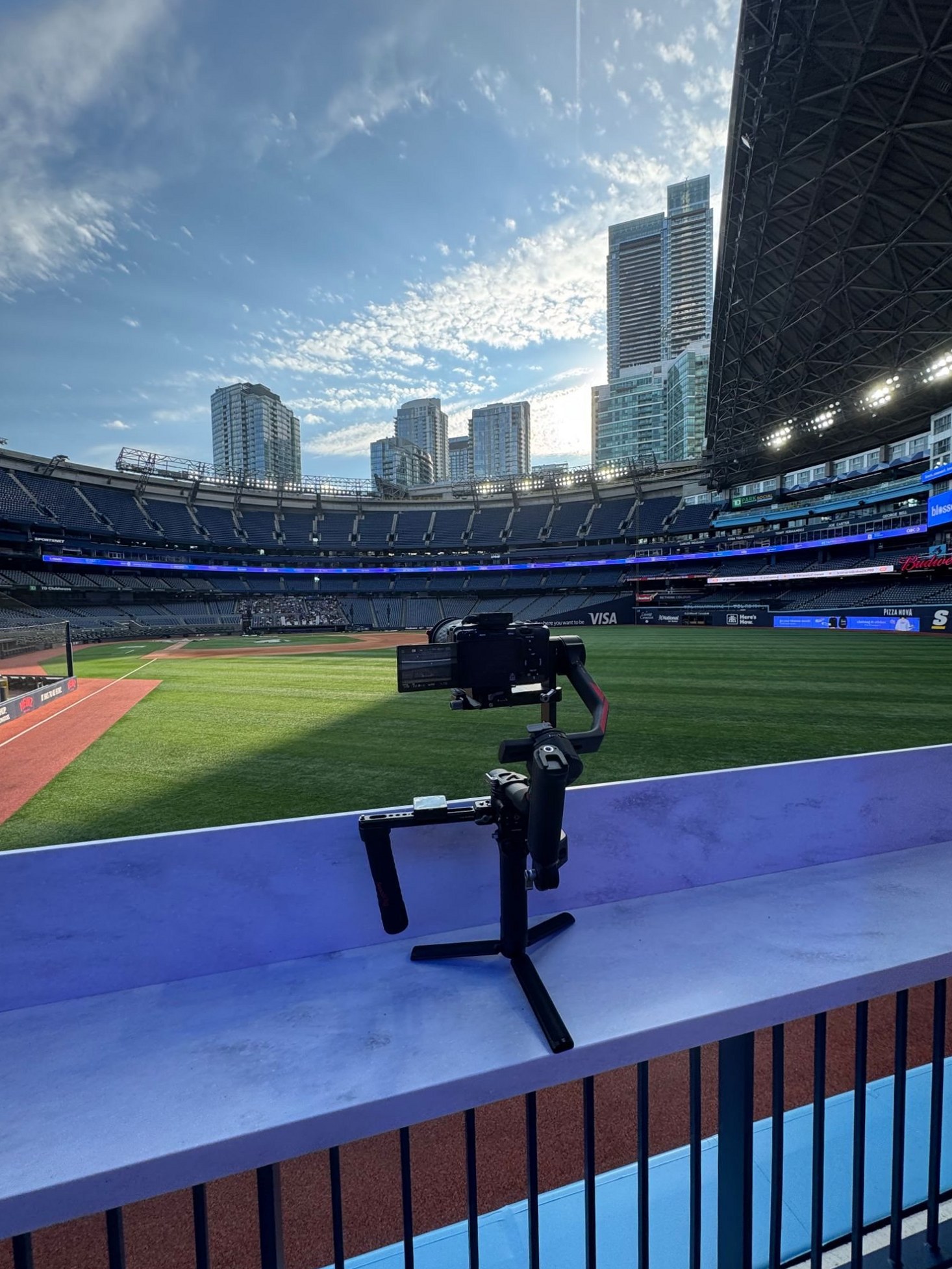 A camera on a gimbal resting on the rail above a Toronto stadium field