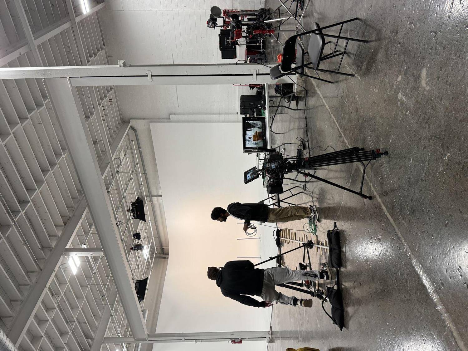 The crew setting up a cinema camera, dolly track and lights in a white Toronto studio