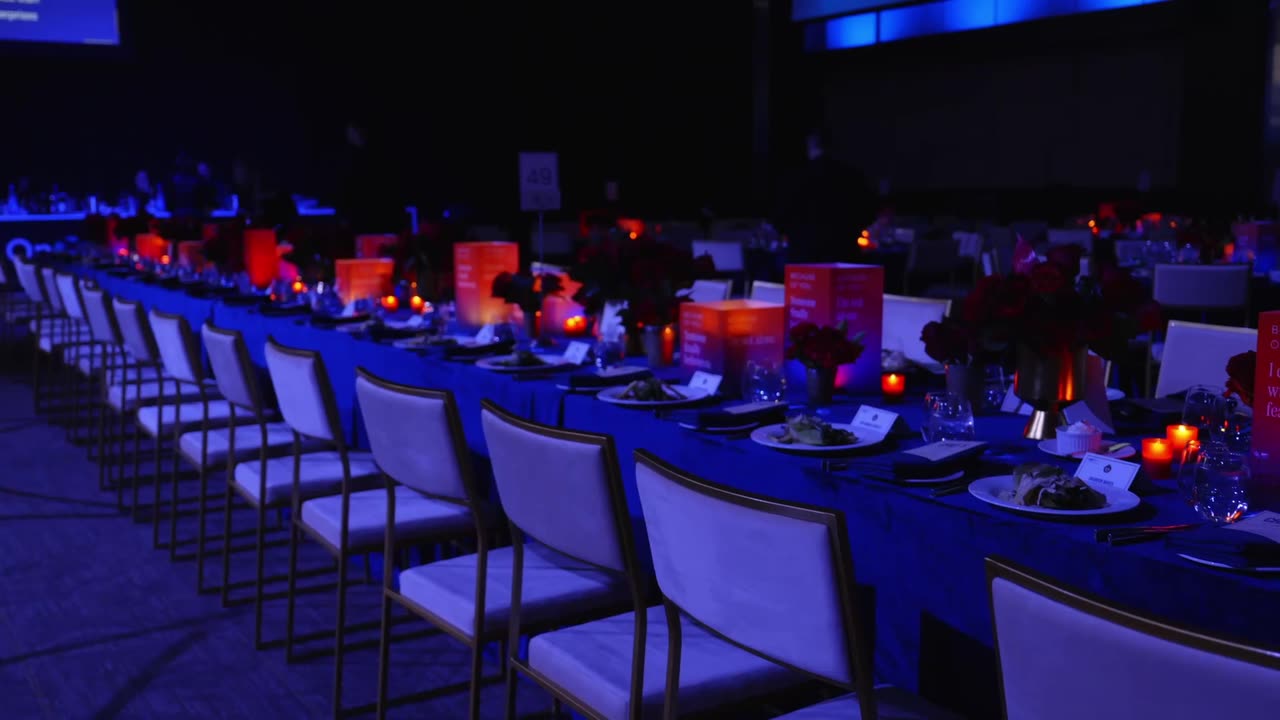 Gala tables set under blue light with red centrepieces