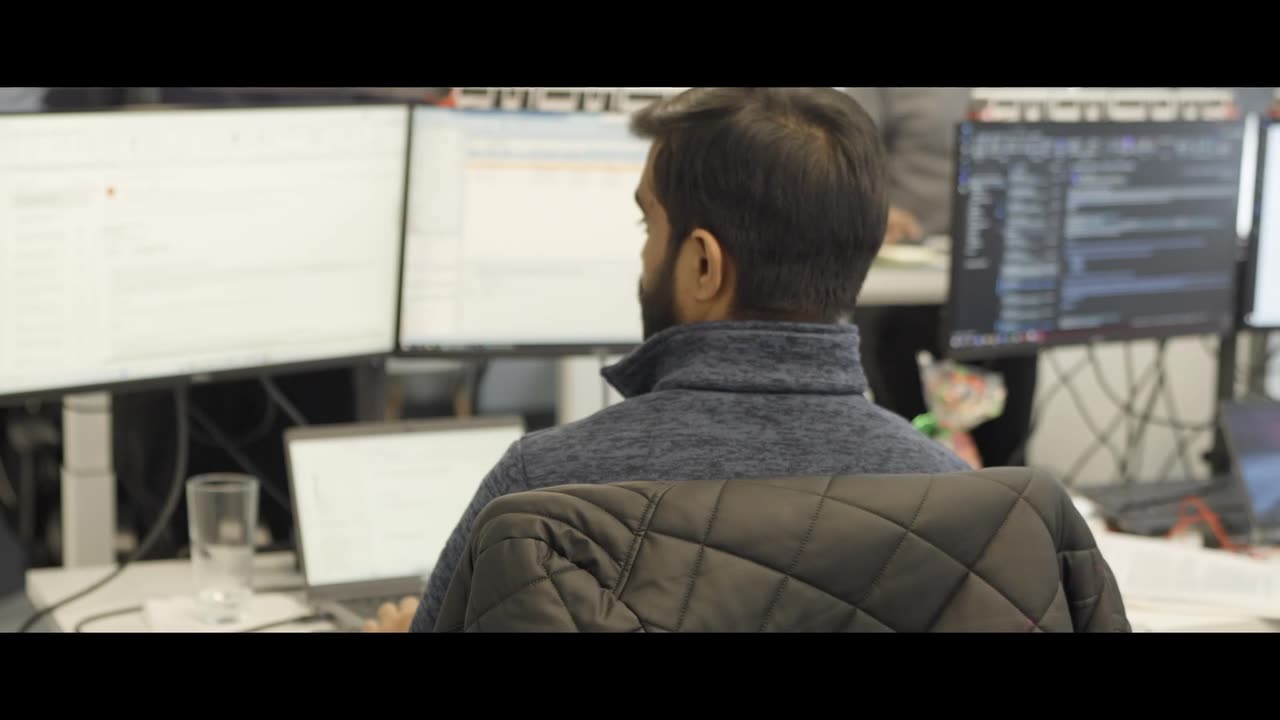 Person working at a desk with several computer screens
